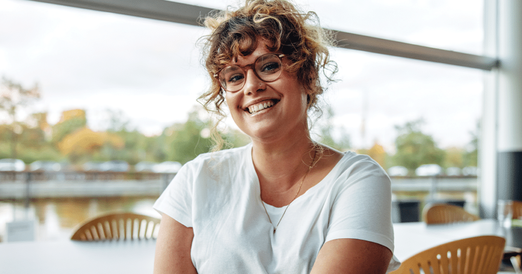 Woman sitting in a cafe smiling.