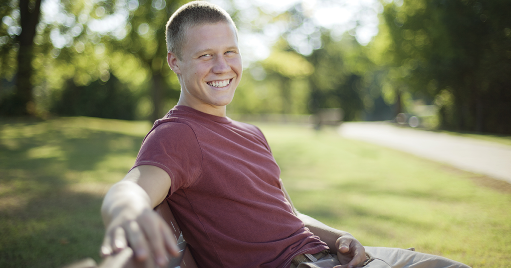 Man sitting on park bench smiling.