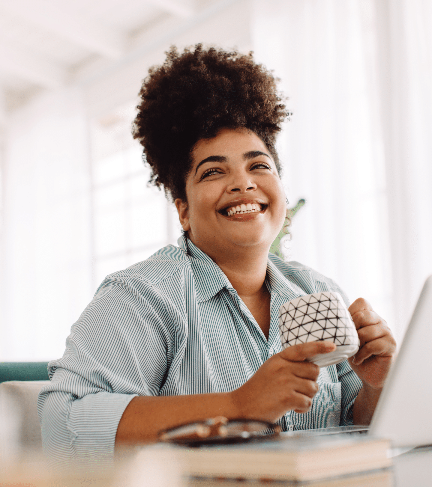 A woman drinks a mug of coffee at her desk.